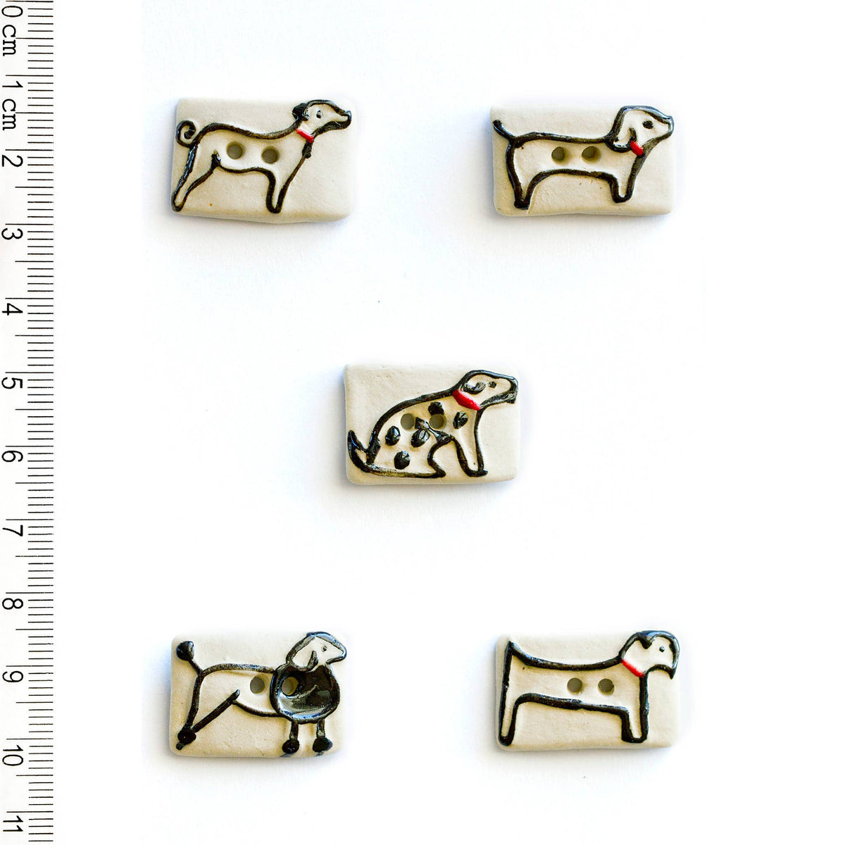 Off-white buttons with dog illustrations on a white background, accompanied by a ruler for scale.