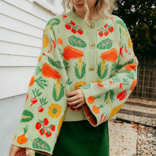 Person wearing a colorful veggie -patterned cardigan outdoors.