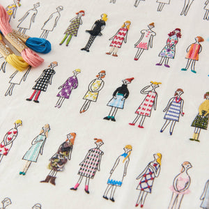Close up of embroidered people in colorful dresses with on a white background