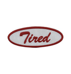 Red and white embroidered patch with 'Tired' text on a white background
