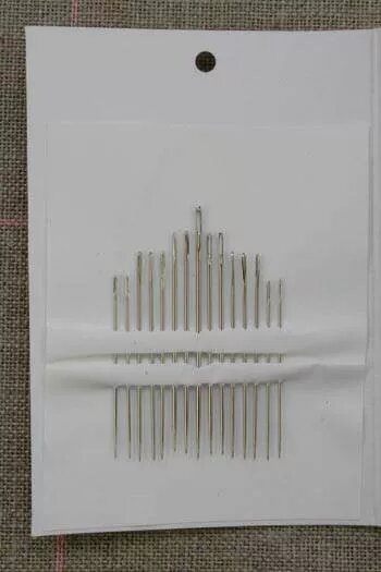Set of needles on a white card with a textured brown background