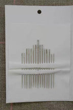 Set of needles on a white card with a textured brown background