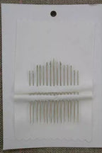 Set of needles in a white cardboard holder on a textured surface