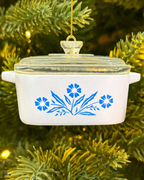 Decorative pot ornament with blue floral design hanging on a Christmas tree.