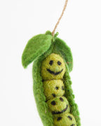 Decorative felt pea pod with a smiling yellow pea inside on a white background