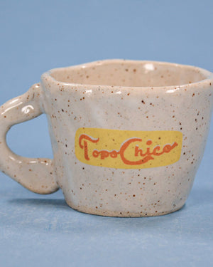 Speckled ceramic mug with 'Toro Chico' logo on a blue background