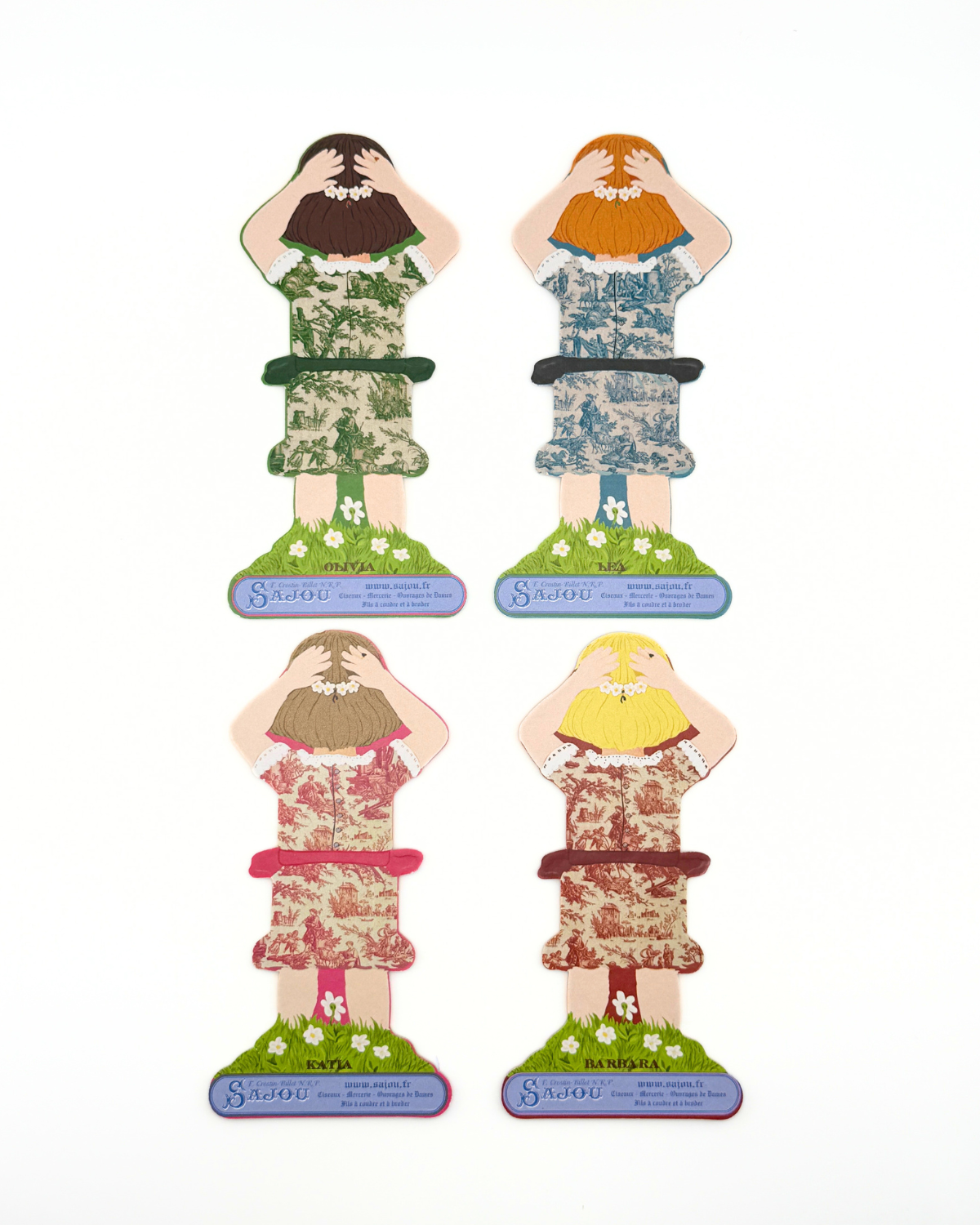 Back of four paper doll thread storage with different dresses on a white background