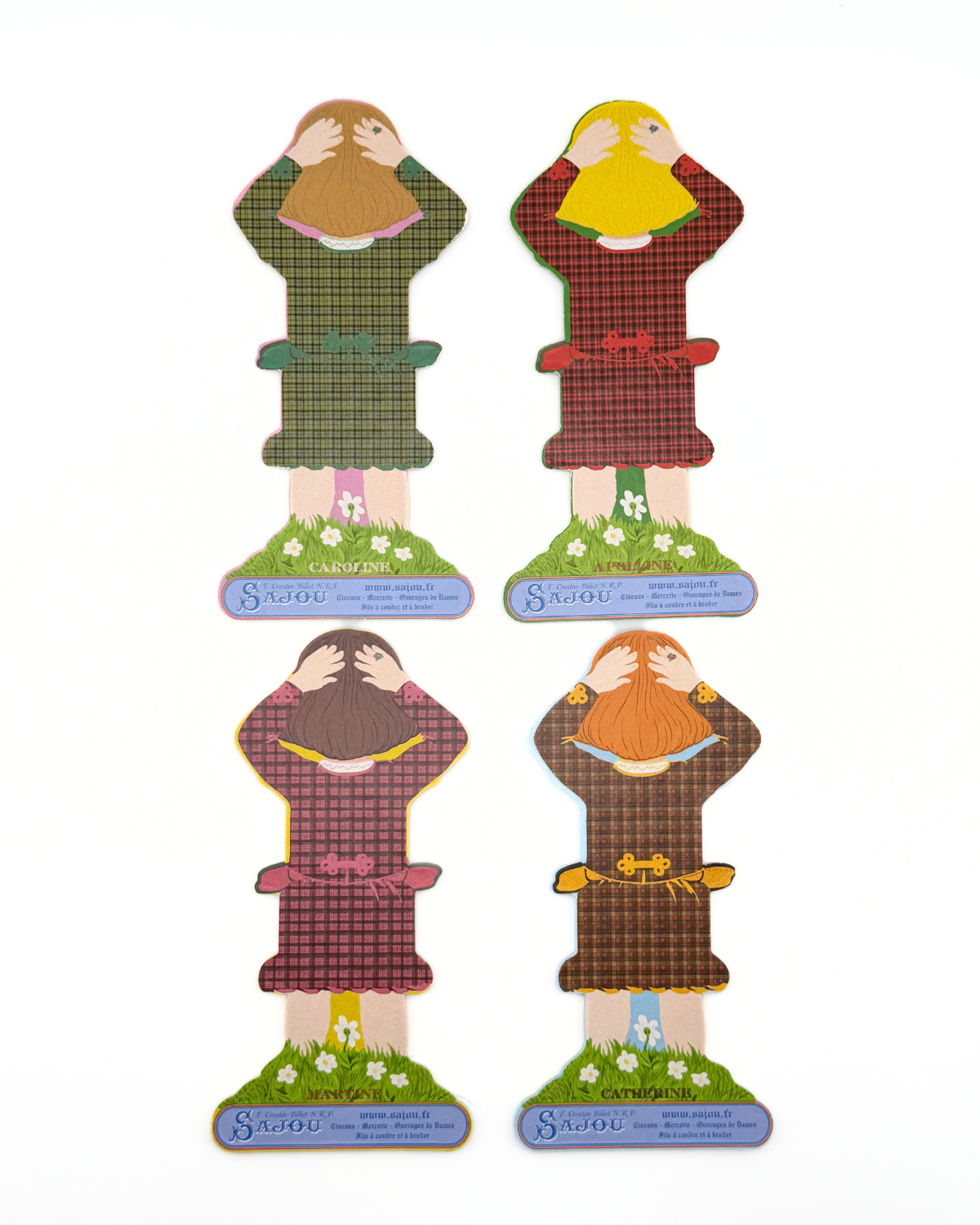 Back of four paper doll thread storage with different dresses on a white background