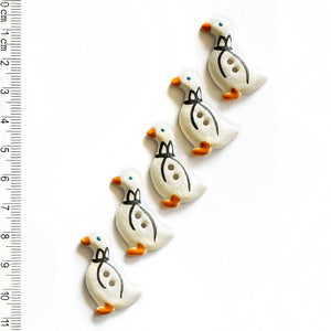 Set of five goose-shaped buttons with a ruler for scale on a white background