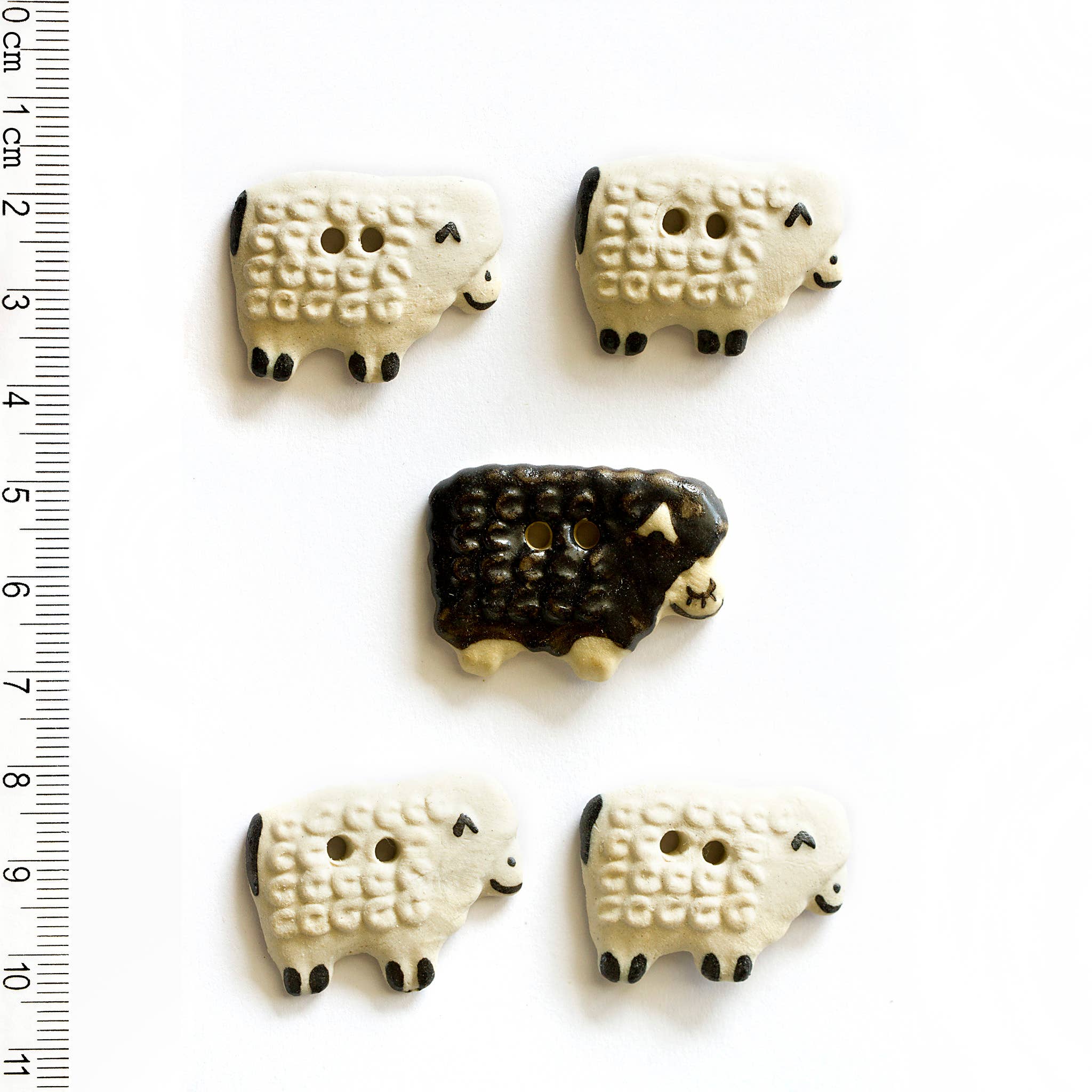 Four white sheep and one black sheep buttons on a white background