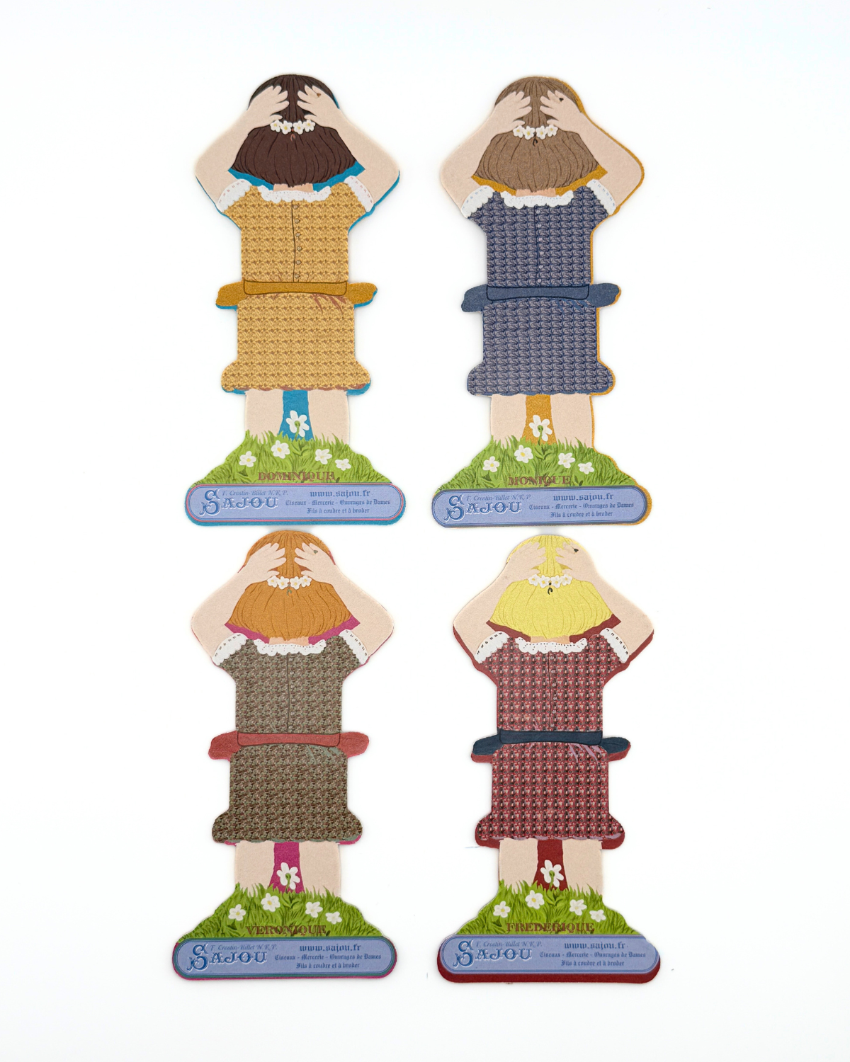 Back of four paper doll thread storage with different dresses on a white background