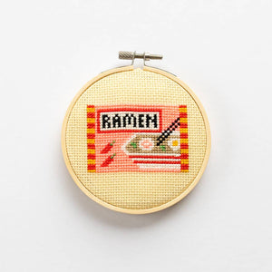 Cross-stitched hoop with 'Ramen' theme on a white background