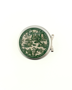 Round green and beige tin with decorative design on a white background