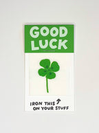 Iron on patch with a green four-leaf clover design on a white background