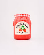 Red jar with strawberry preserve label on a light gray background