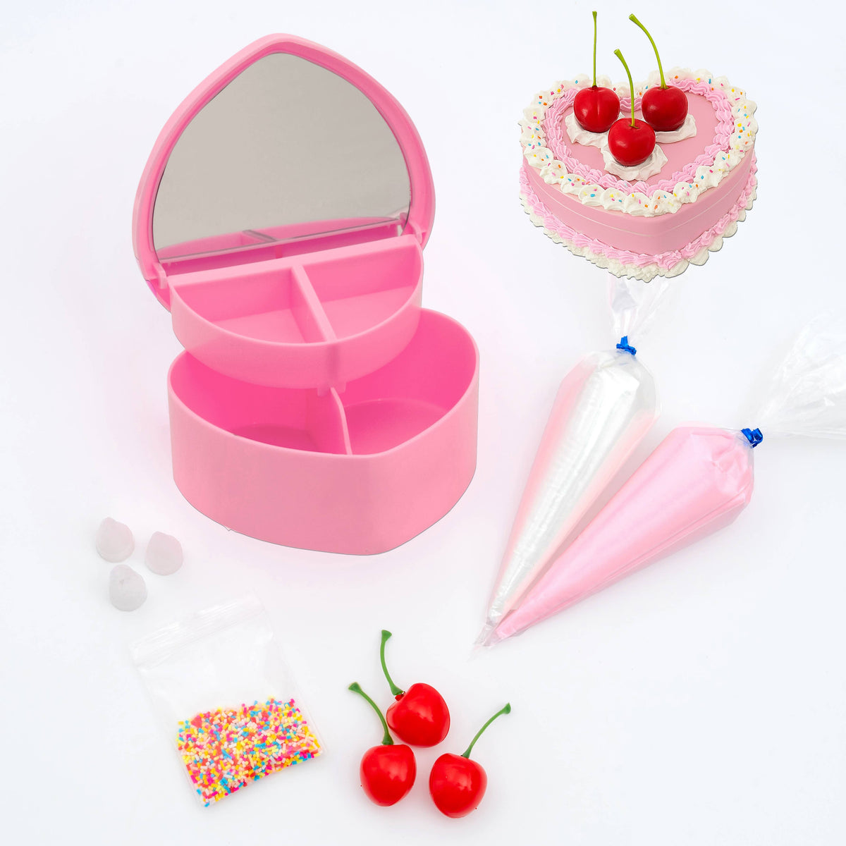 Pink heart-shaped jewelry box with cake decorating tools on a white background
