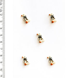 Five tiny geese-shaped buttons on a white background with a ruler for scale.