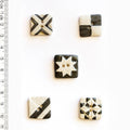 Five black and white decorative buttons with geometric patterns on a white background, accompanied by a ruler for scale.