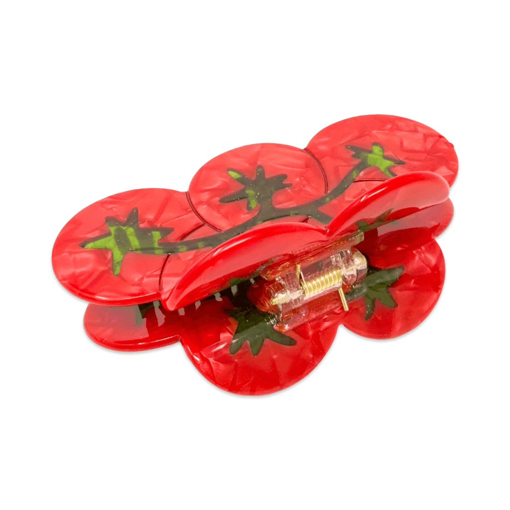 Back of red tomato-shaped hair claw
clip with green stems on a white background