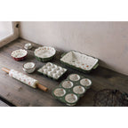 Set of ceramic kitchenware including bowls, a rolling pin, and a muffin tin on a wooden surface.