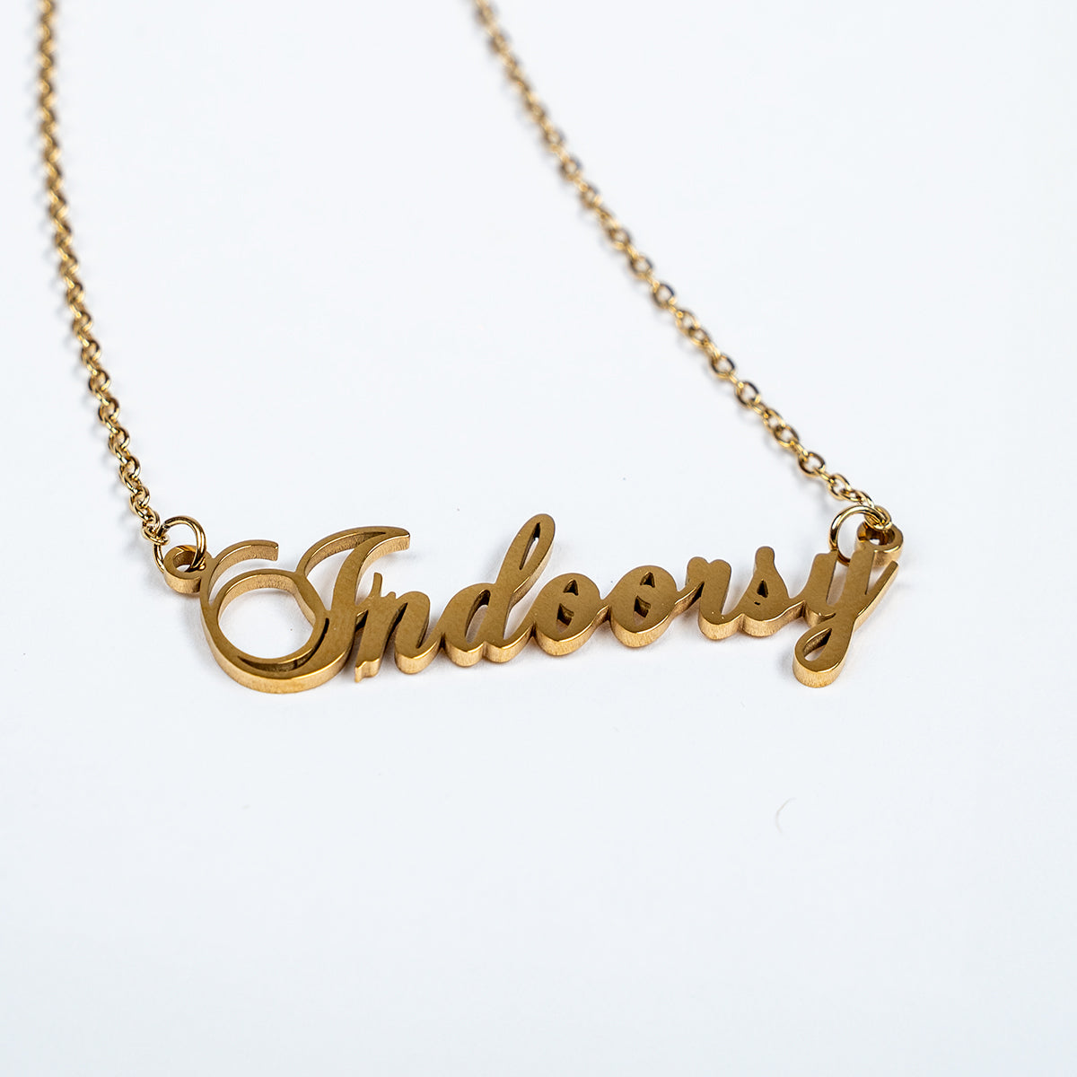 Gold necklace with 'Indoorsy' pendant on a white background