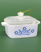 White ceramic ornament with blue floral design on a green background