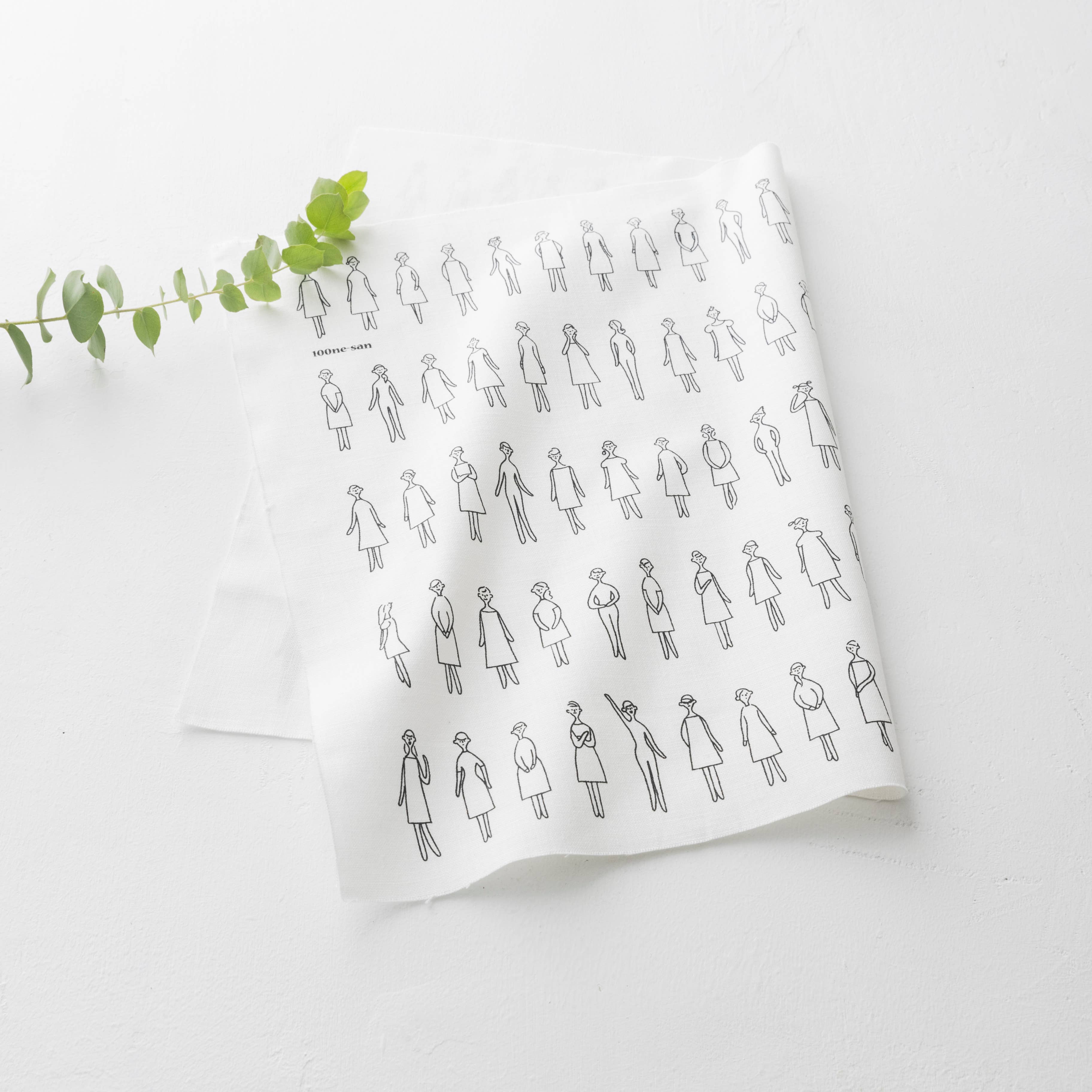 White fabric with black line art pattern of people wearing dresses on a white background