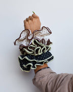 Hand wearing multiple ruffled scrunchies on a white background
