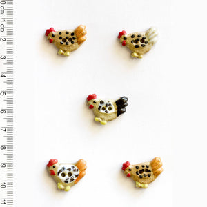 Five chicken-shaped buttons on a white background with a ruler for scale.