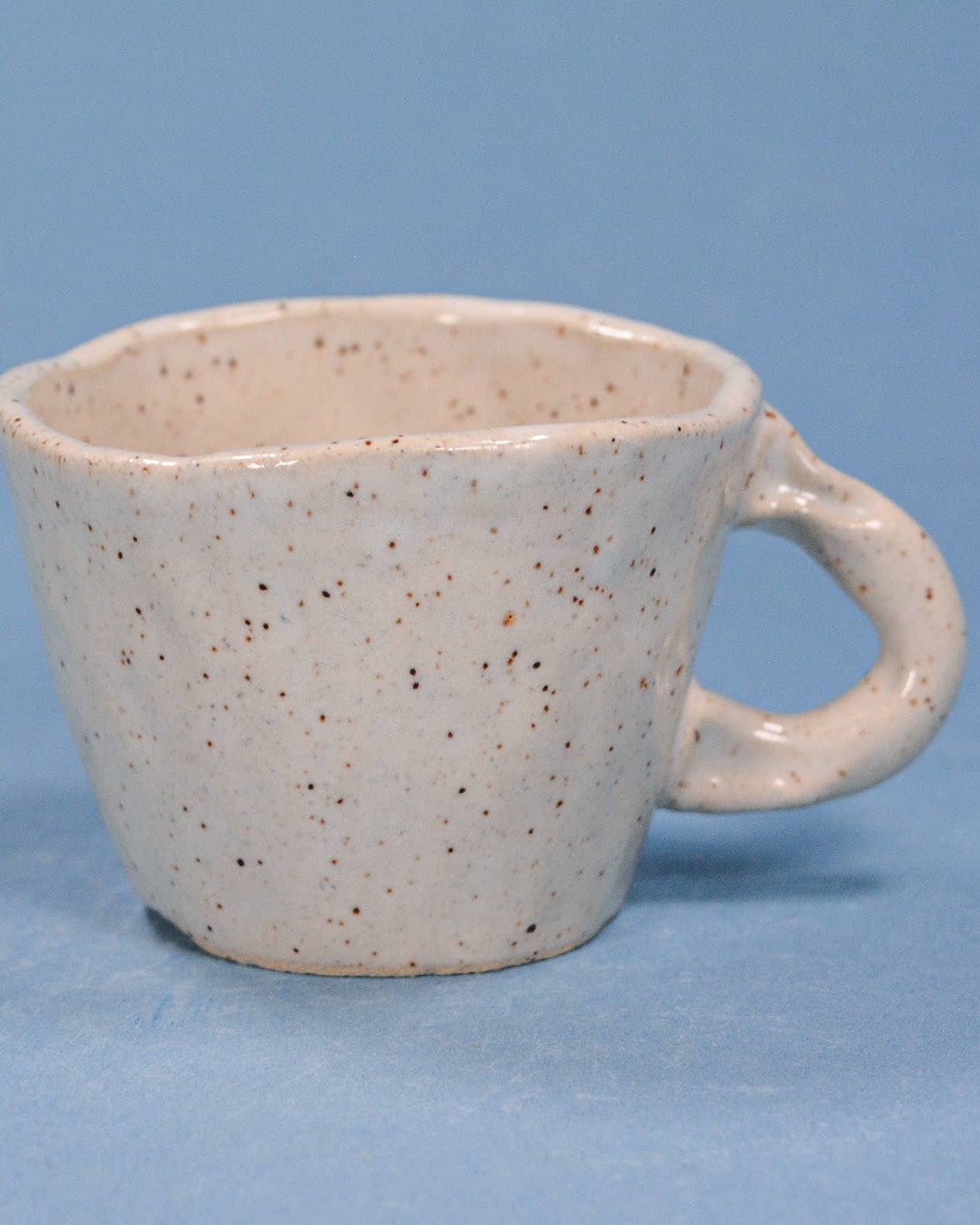 Speckled ceramic mug on a blue background