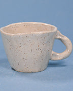 Speckled ceramic mug on a blue background