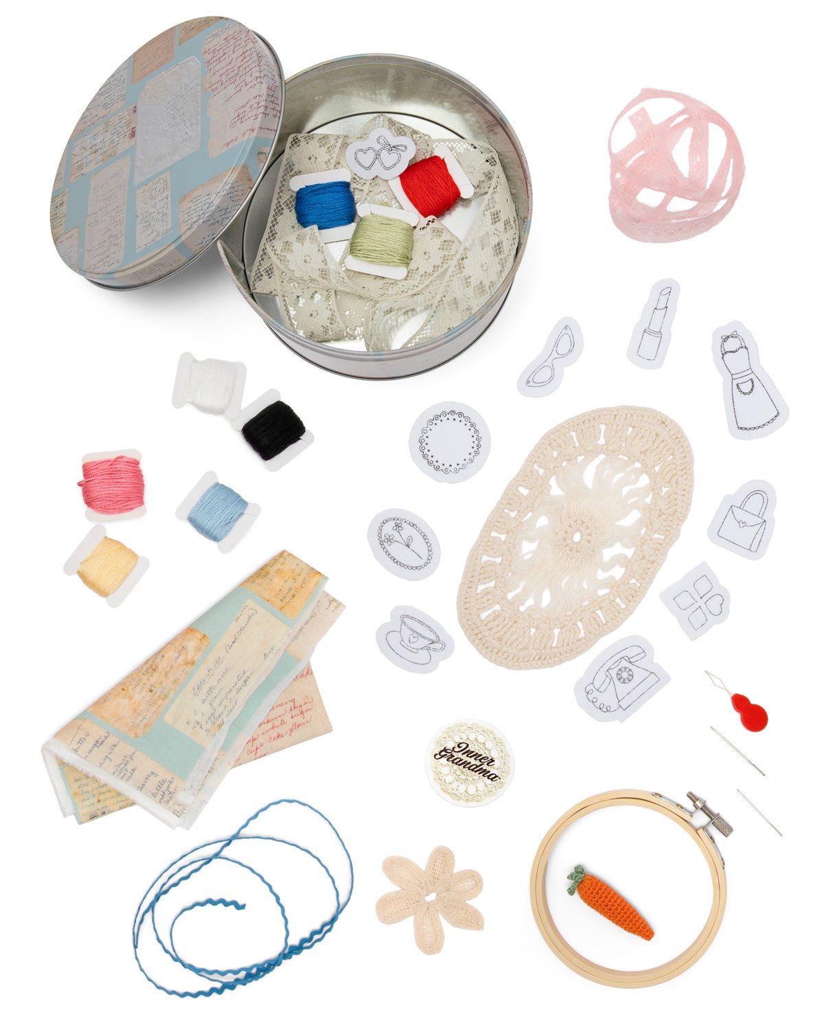Collection of sewing and crafting supplies including a tin, thread, scissors, and decorative elements on a white background.