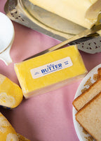 Butter candle, bread slices, and a measuring cup on a pink table cloth at breakfast.