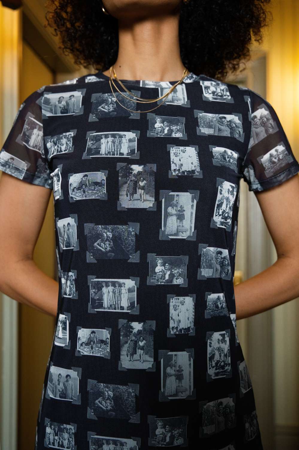 Front of person wearing black and gray mesh fabric dress with printed black and white images of grandmas, people and objects, standing indoors.