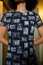 Front of person wearing black and gray mesh fabric dress with printed black and white images of grandmas, people and objects, standing indoors.