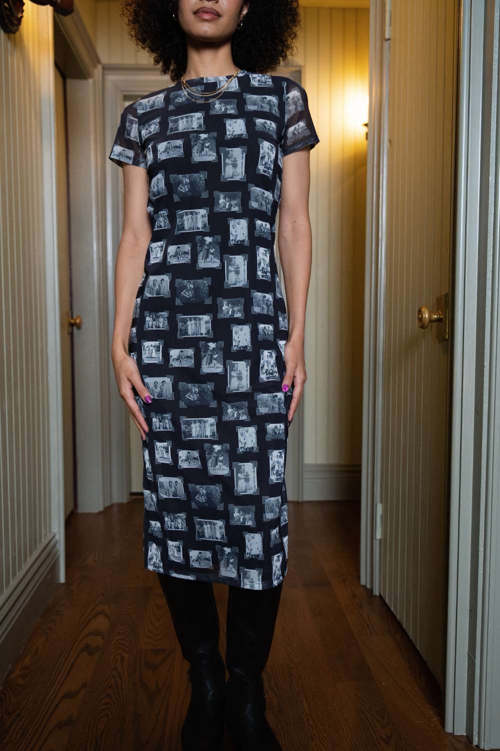 Person wearing black and gray mesh fabric dress with printed black and white images of grandmas, people and objects, standing indoors.