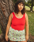 Person wearing a red tank top and green-and-white gingham skort with a fruit print.