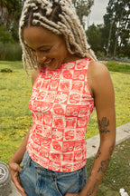 Person wearing a tank top with orange vintage-style food coupon pattern and jeans.