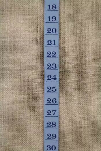Blue measurement tape ribbon with numbers on a beige fabric background