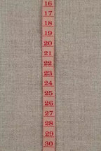 Measuring tape ribbon with red numbers on a textured beige background