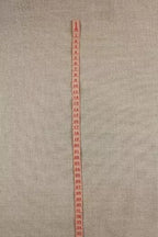 Measuring tape ribbon with red markings on a beige fabric background
