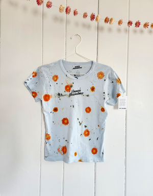 Short-sleeve light blue cropped baby tee shirt with floral pattern naturally dyed by flowers with "Inner Grandma" text