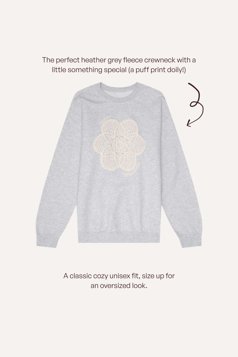 A light heather grey crewneck sweatshirt with a cream puff-print dolly graphic on the chest, shown on a light beige background with descriptive text and a brown arrow.