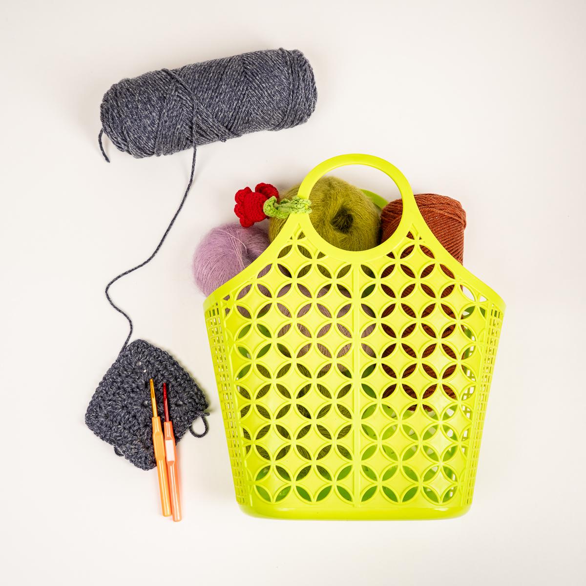Yellow perforated basket with yarn and knitting tools on a white background