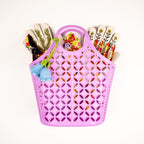 Pink perforated basket with gardening tools on a white background
