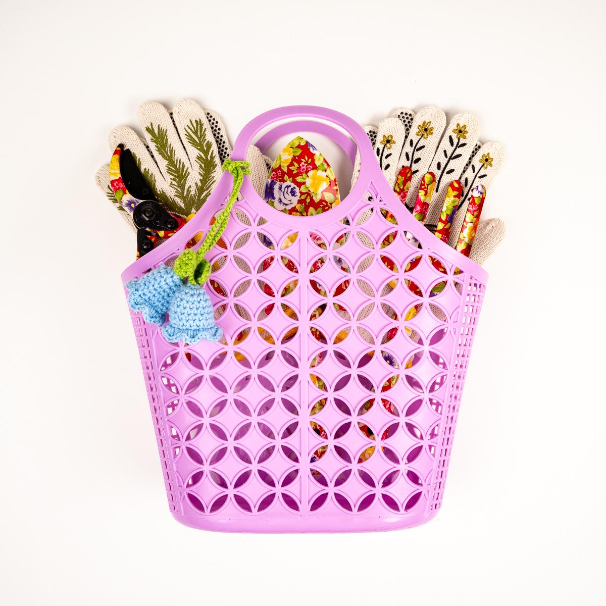 Pink perforated basket with gardening tools on a white background