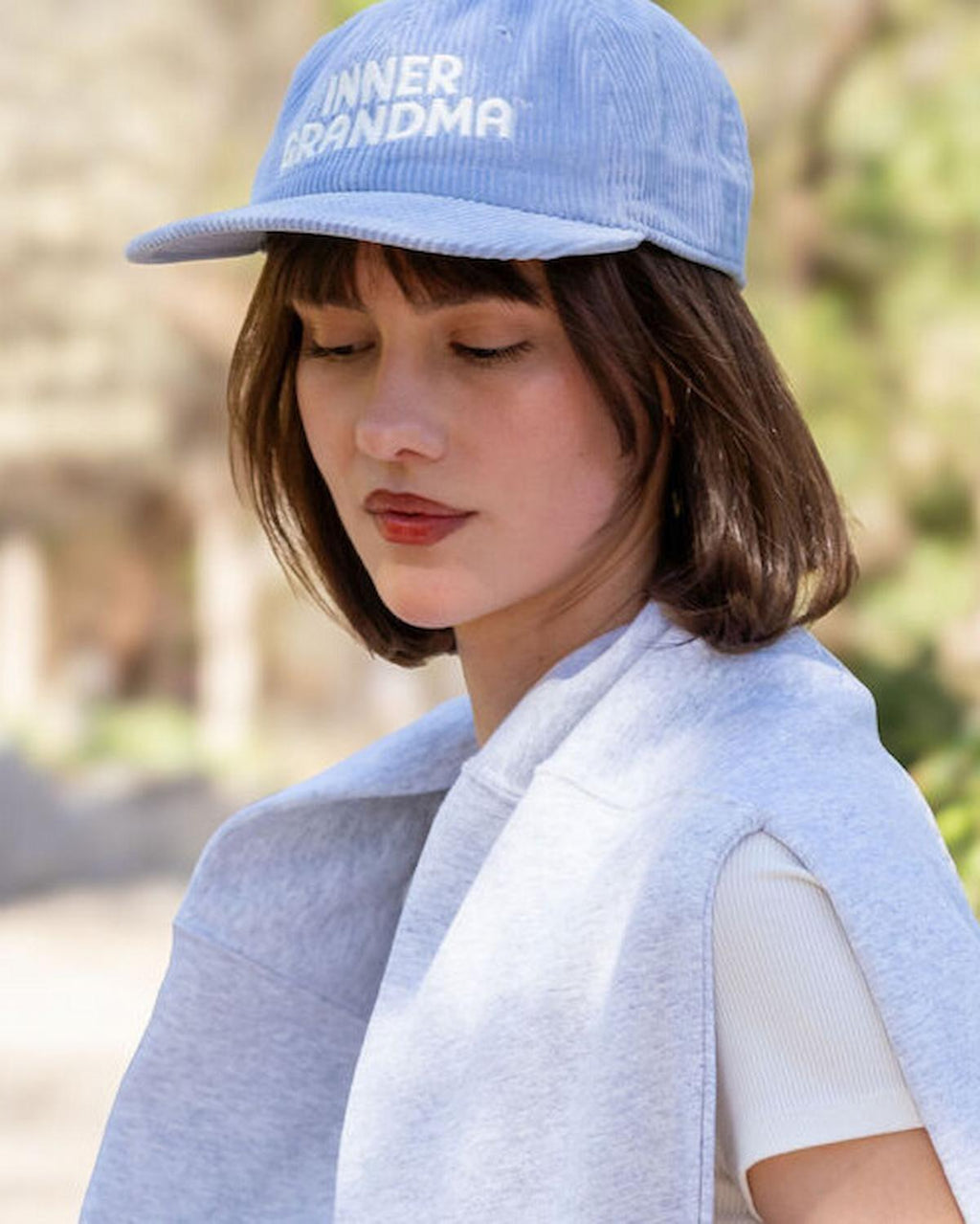 Woman wearing a blue cap with 'Niner Grandma' text, outdoors.