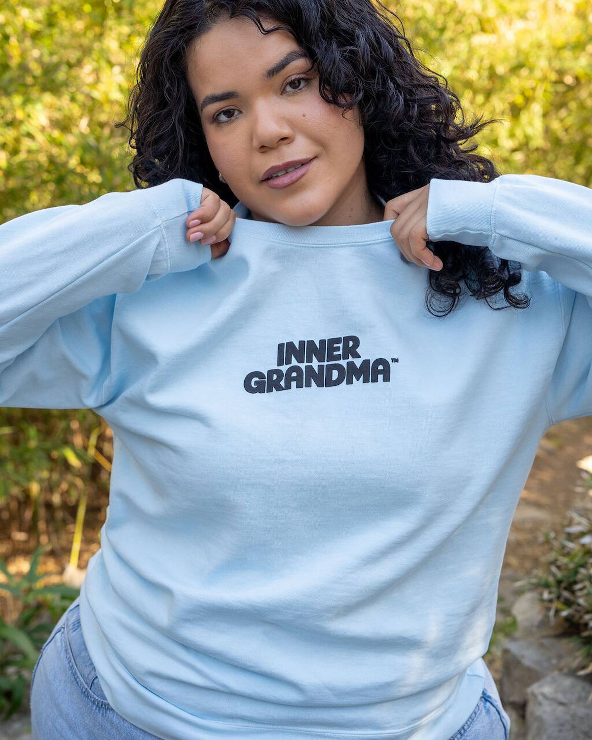 Person wearing a light blue sweatshirt with 'INNER GRANDMA' text, standing outdoors.
