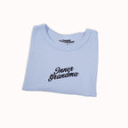 Light blue cropped baby t-shirt with 'Inner Grandma' text on a white background