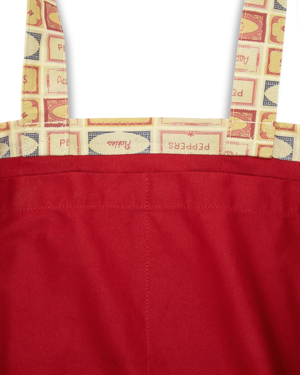 Inside of patterned fabric with vegetable labels of pickles, peppers, tomatoes, asparagus and onions on a white background